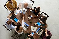Von oben: Personen an einem Tisch arbeiten zusammen